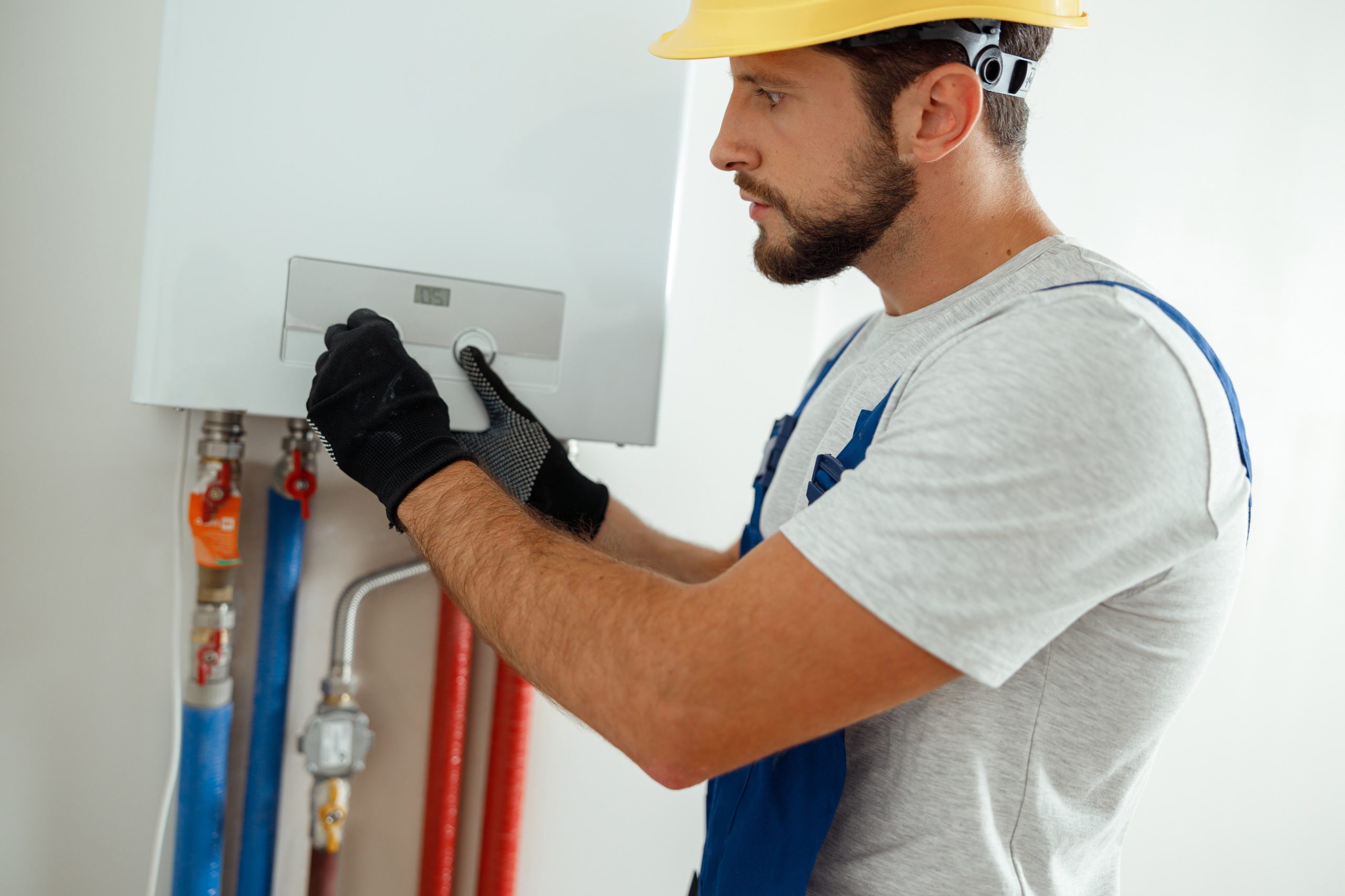 Serious technician setting the new gas boiler for hot water and heating Serious technician setting the new gas boiler for hot water and heating. Manual work, maintenance concept